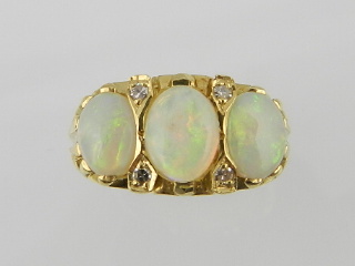 A Victorian style 18 carat yellow gold diamond and opal ring, set three cabochon opals flanked by