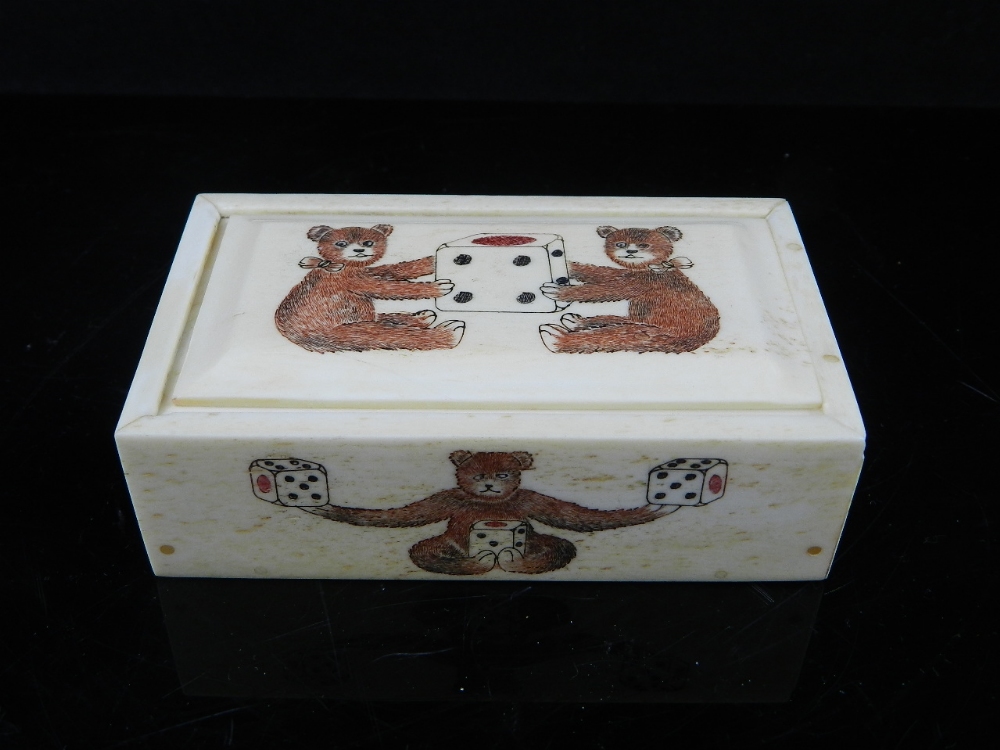 An unusual engraved bone dice box decorated with teddies and enclosing six bone die. W: 9cm
