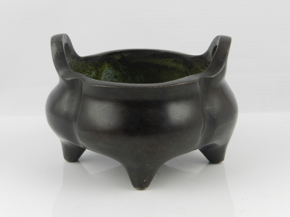 A Chinese bronze incense burner, lobed, oval form with pierced side handles on four peg feet.