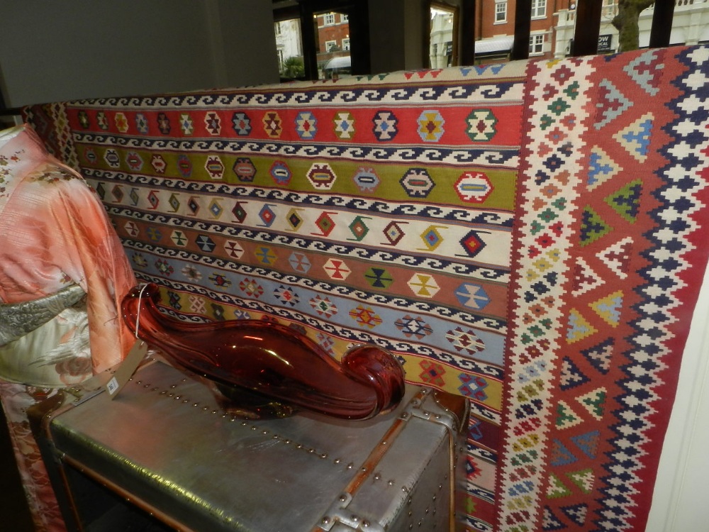 A Persian Kelim rug, decorated with geometric medallions on a multi-coloured striped ground, multi-