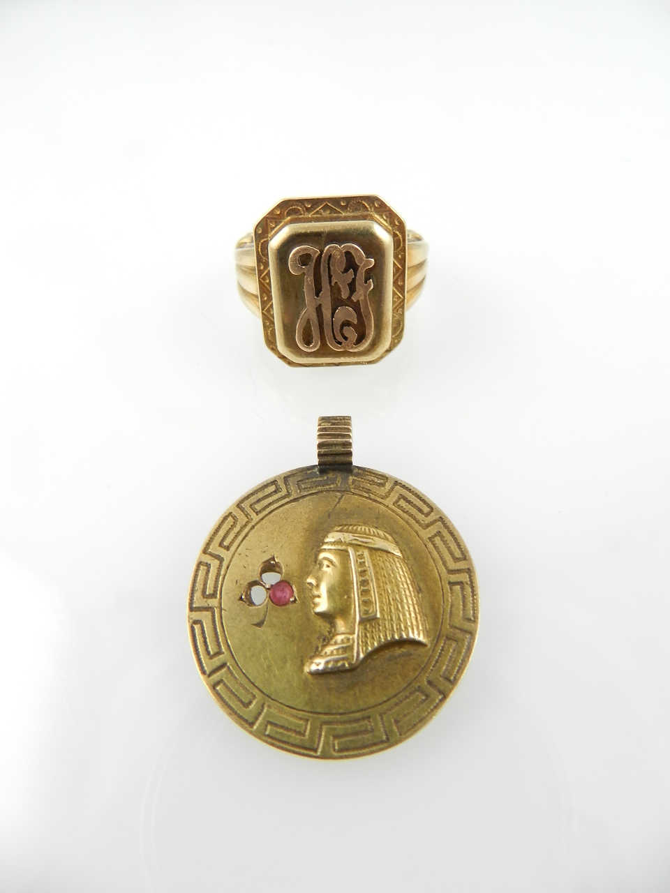 A yellow metal signet ring, monogrammed 'H.F.' together with an Egyptian revival pendant.