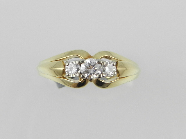 A yellow metal three stone diamond ring.