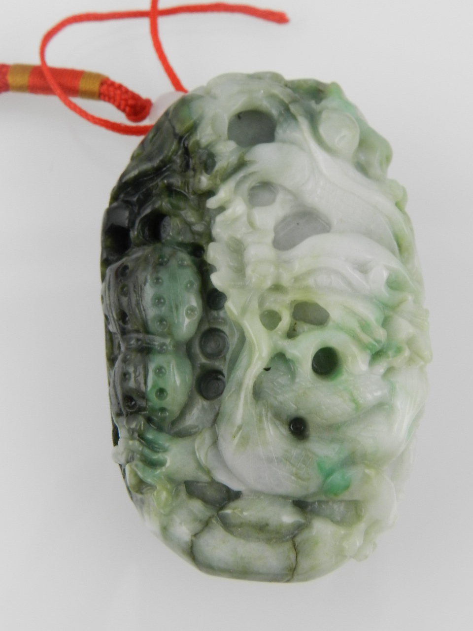 A variegated green and white jade pendant, carved with a dragon. L: 8cm