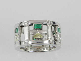 An unusual white metal emerald and diamond set dress ring in the modernist style, set with