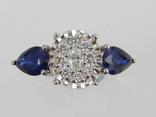 A white metal diamond and sapphire dress ring, centred with diamonds of multiple cuts, flanked by