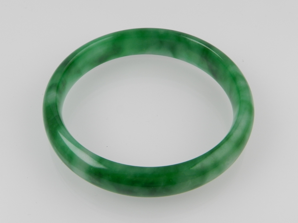 A Chinese mottled green jadeite bangle, external diameter 8.5 cm.