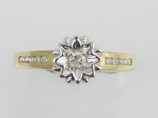 A 9ct yellow gold diamond dress ring centred with an illusion set diamond with diamond shoulders.