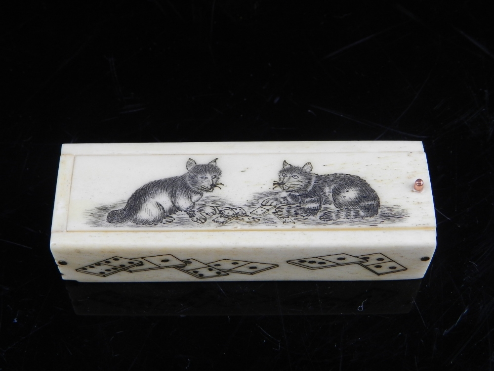 A carved bone domino box, the sliding cover decorated with stylised cats and enclosing set of