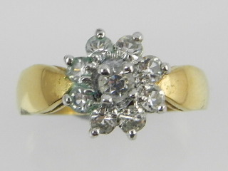 A yellow metal dress ring set with paste in a flower head design.