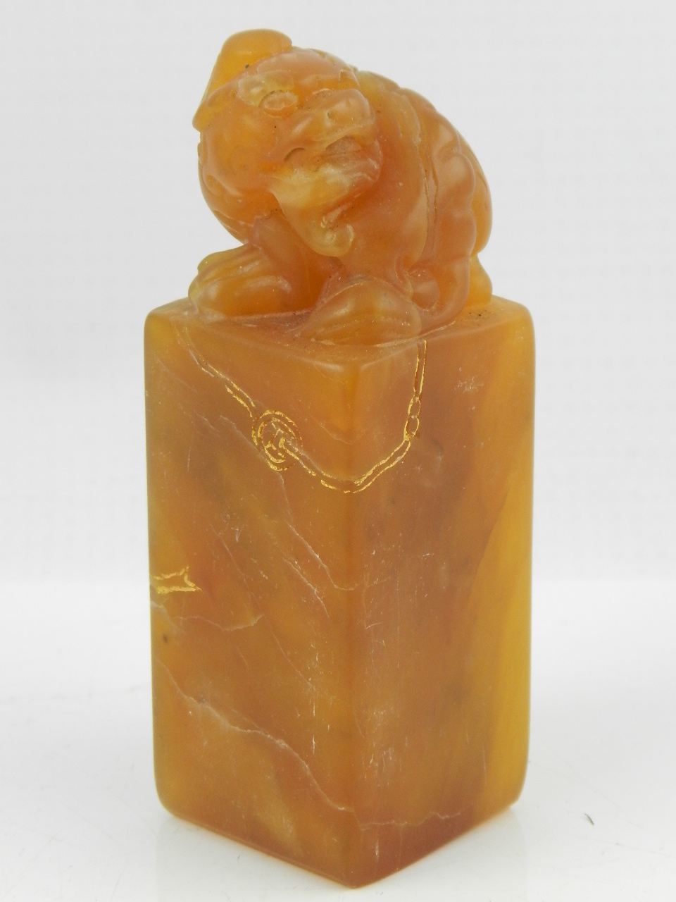A Chinese yellow soapstone seal, carved in the form of a lion with gilt decoration.