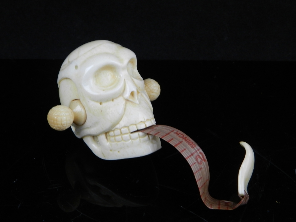 A novelty carved skull tape measure. H: 5cm