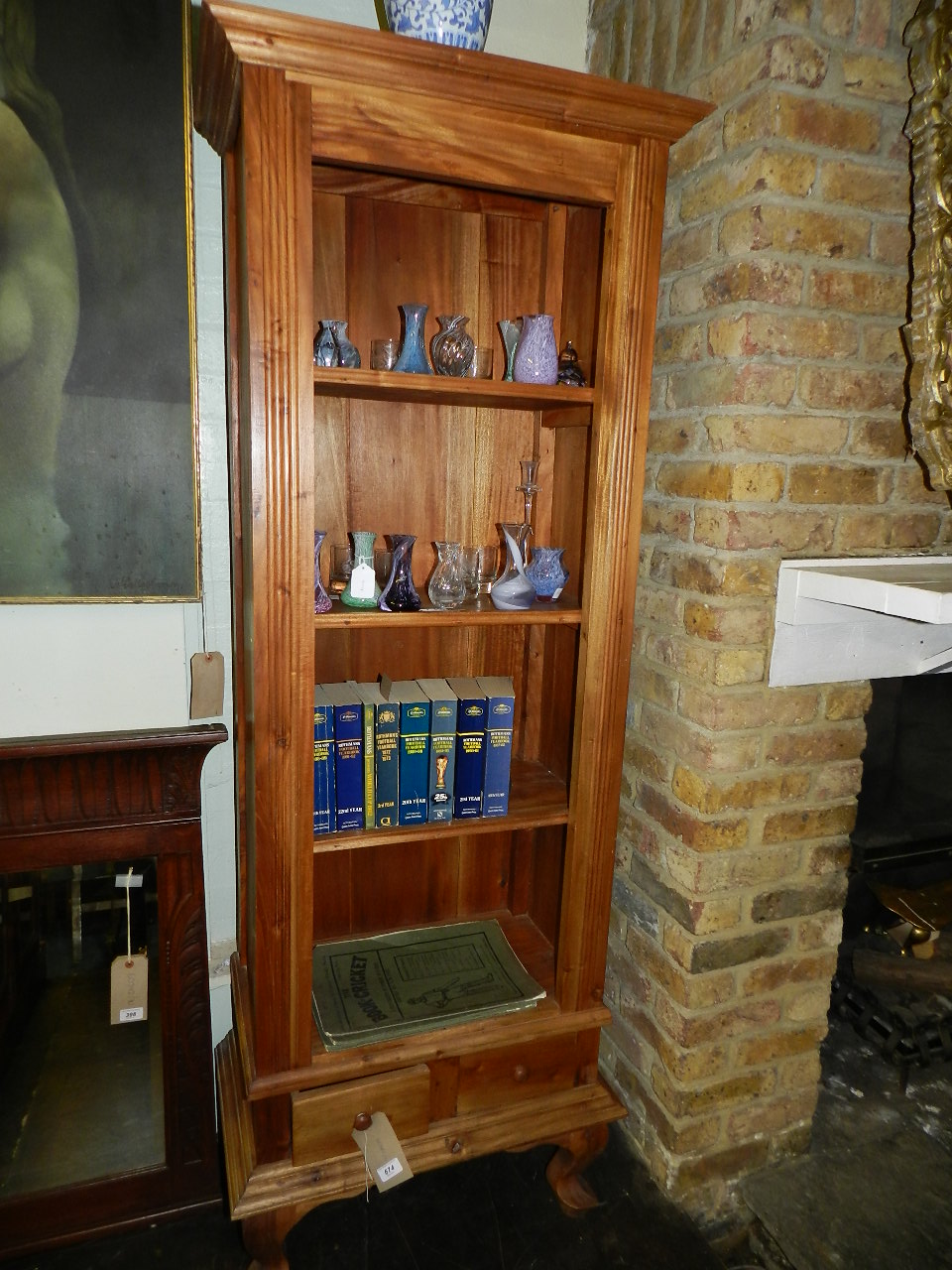 A pine pedestal bookcase having an arrangement of three shelves above two drawers raised on carved