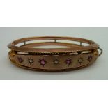 A 9ct gold, diamond and red stone bangle