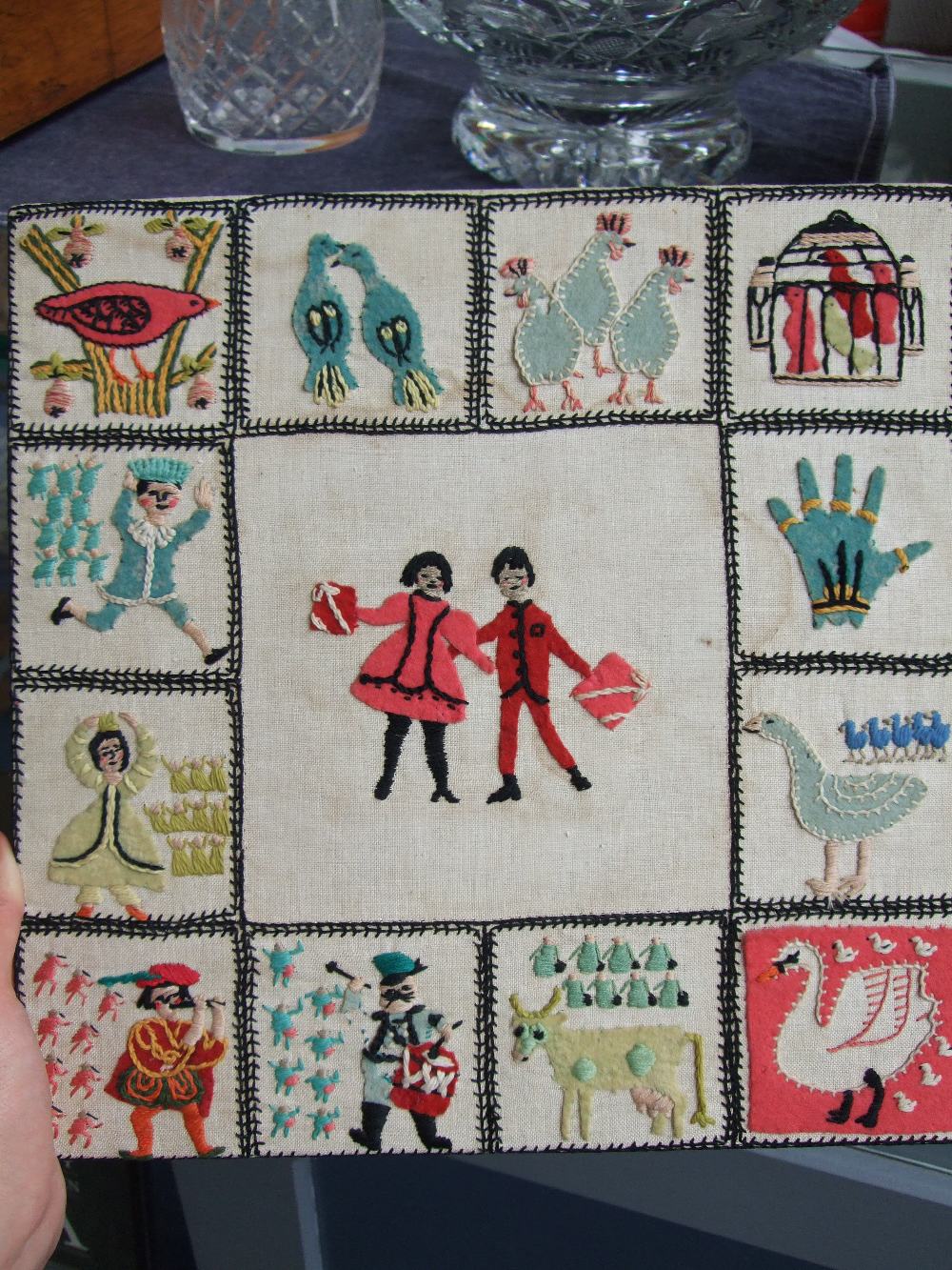 An needlework sampler of the Twelve Days of Christmas, 32 x 32cm.