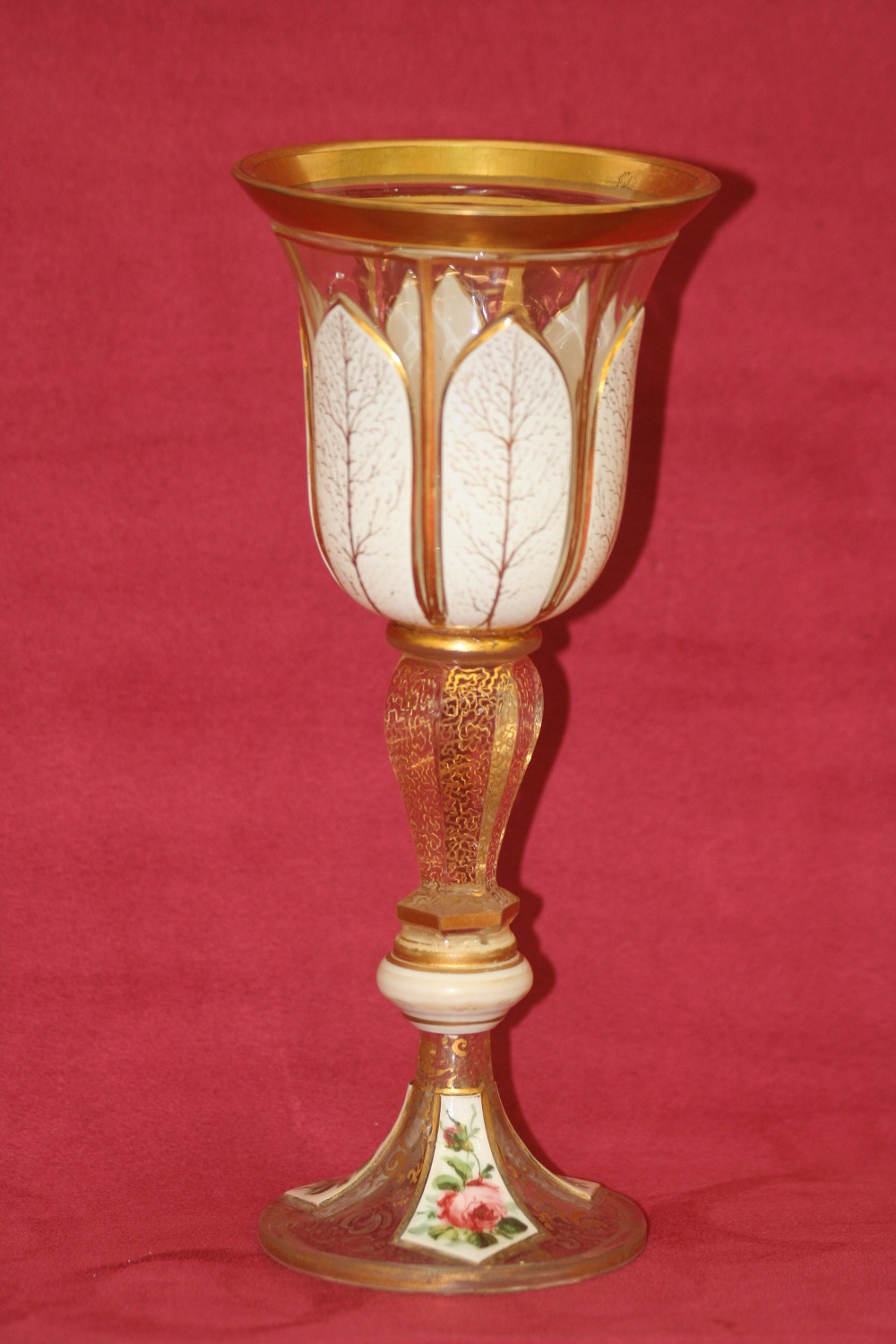 A Victorian overlaid glass goblet, decorated with foliate sprays heightened in gilt, on a baluster