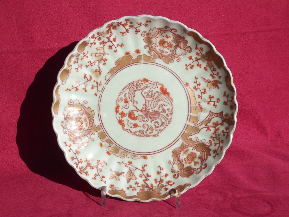 A Japanese scallop bordered plate, having gilt prunus decoration on a celadon ground, four character