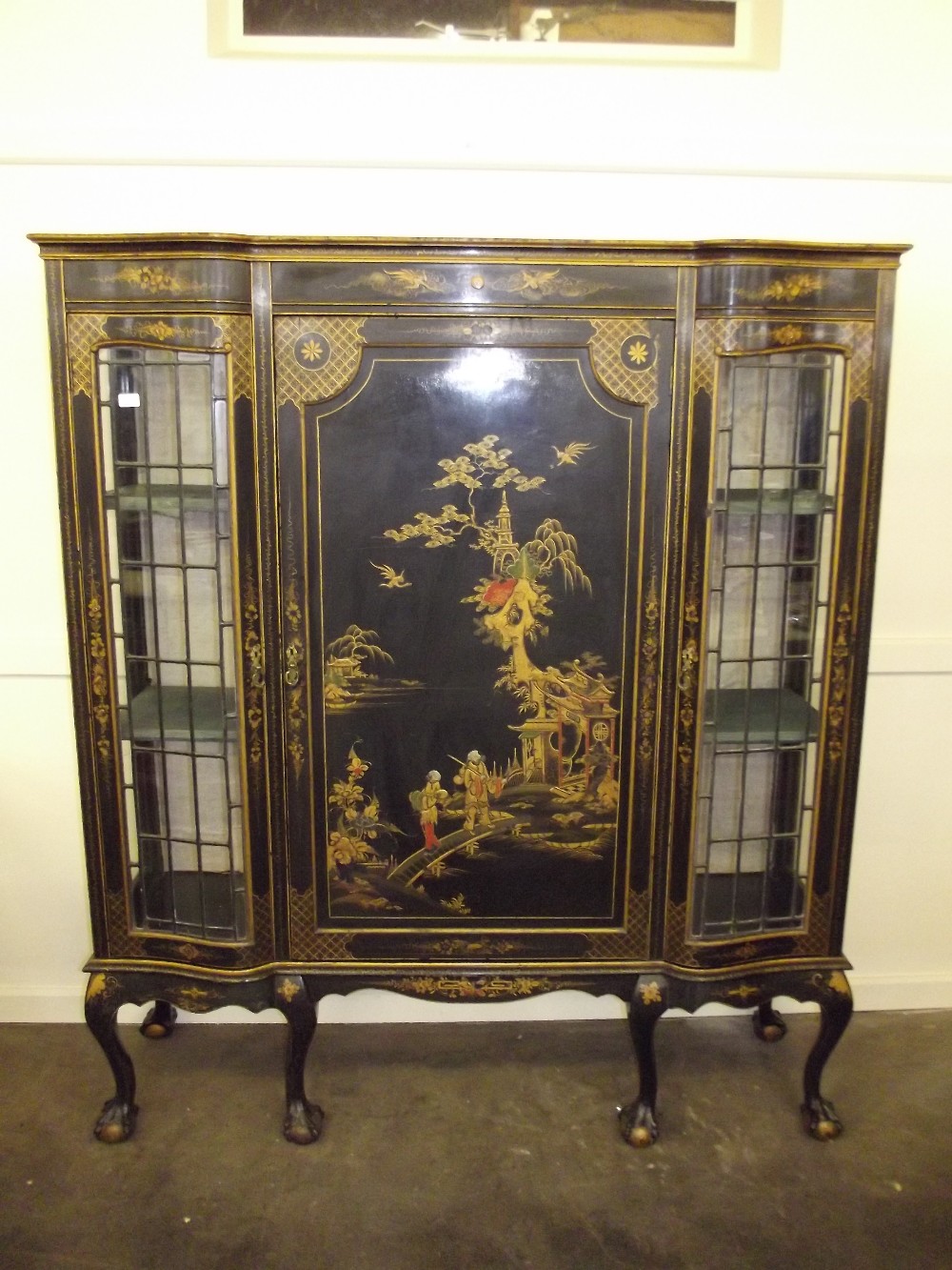 An early 20th Century black chinoiserie cabinet, central cupboard enclosing two shelves flanked by