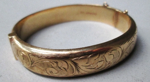 A 9ct gold slave bangle with leaf scroll engraved decoration [approximate weight 18.4g]