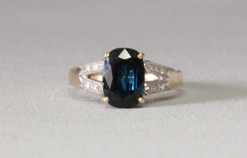 An oval dark blue sapphire [approximate weight 2.50ct] ring with split diamond set shoulder in