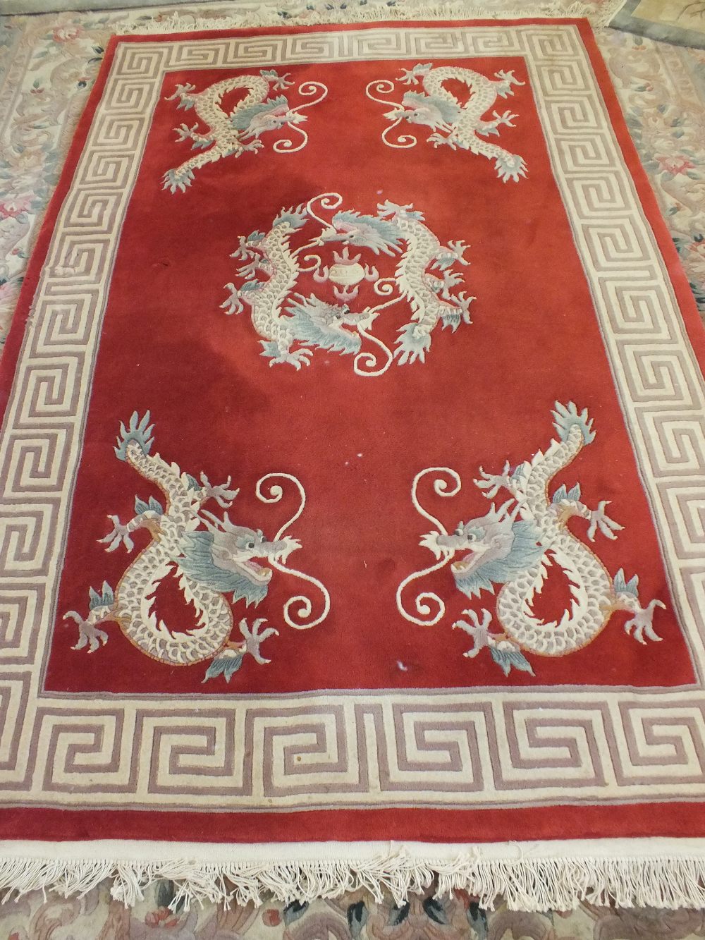 A Chinese red ground dragon decorated carpet, 106" x 70"