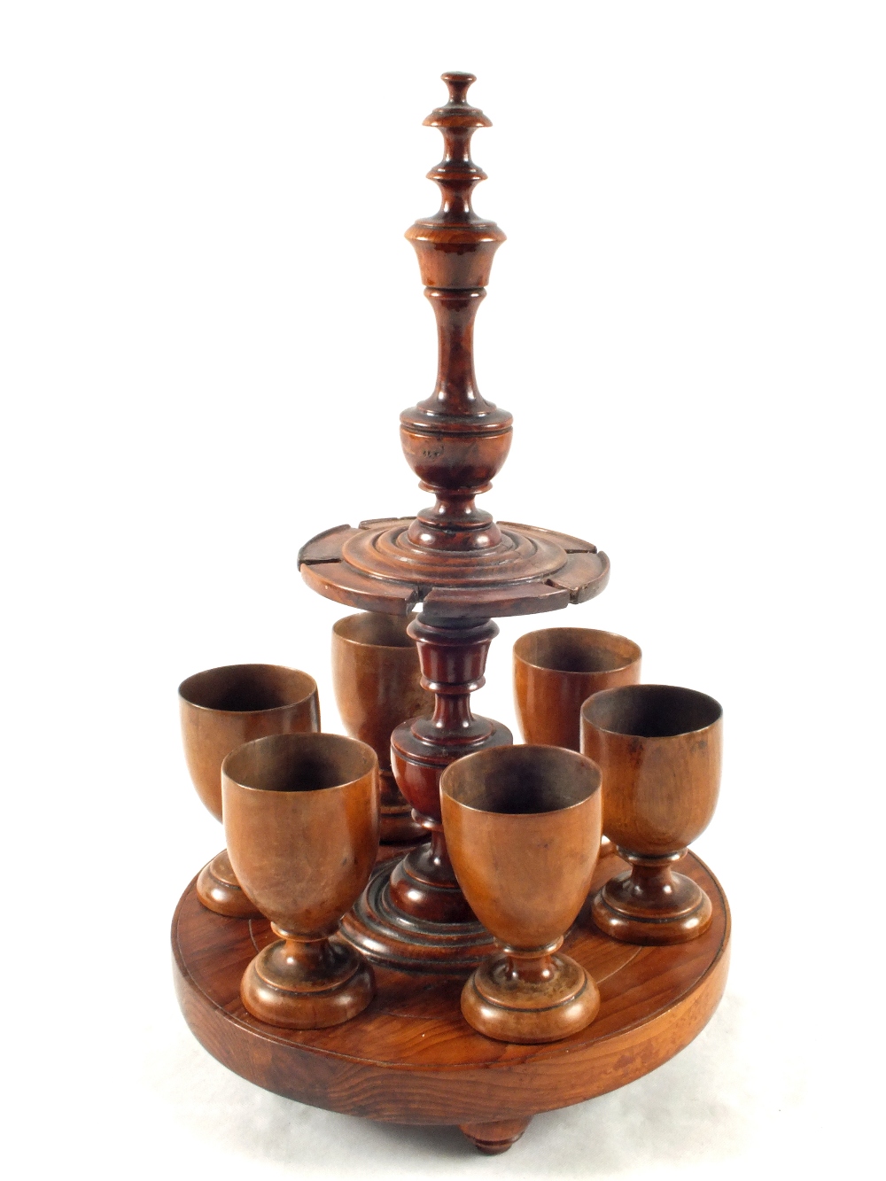 A 19th Century yew wood egg cup stand with six turned wood egg cups