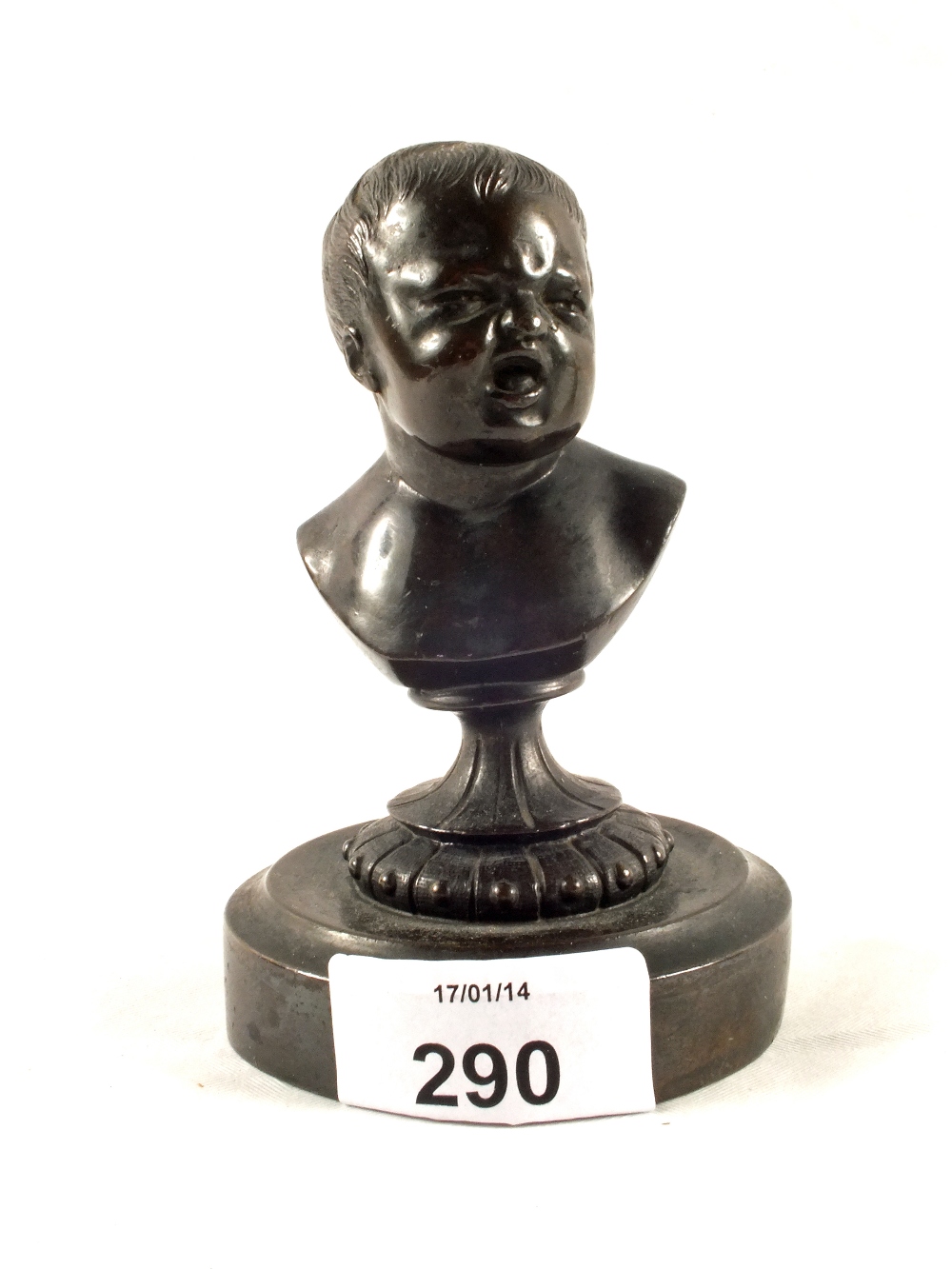 A small metal bust of a miserable baby