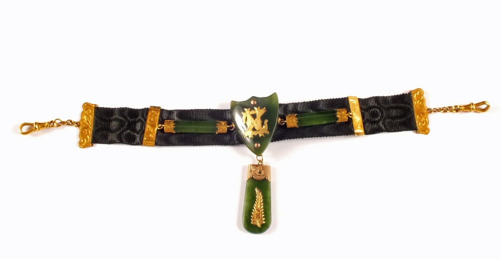 A Gold and silk watch band with Jade shield and Gold overlay to centre with a New Zealand emblem