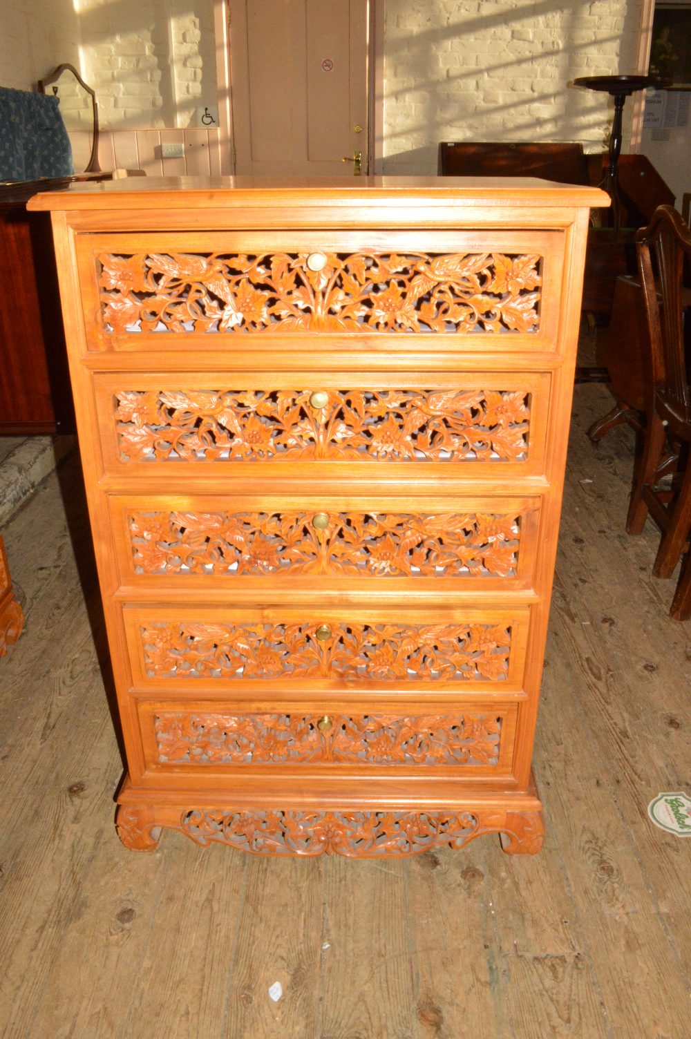 A pair of elaborately carved five drawer chest of drawers and a TV unit