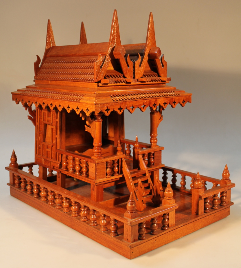 A heavily carved hardwood model of an oriental spirit house, of stained form, decorated on a