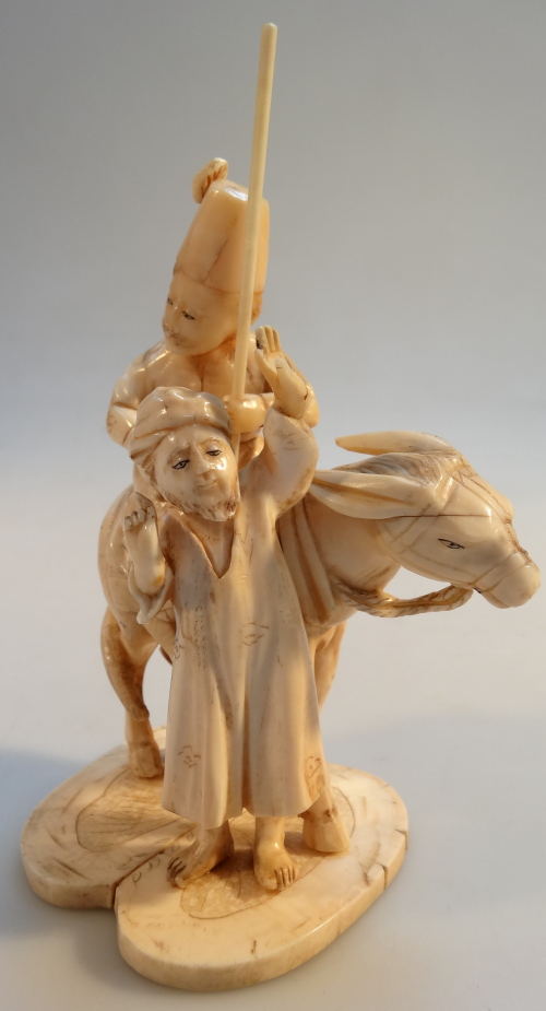 An early 20thC Japanese carved ivory figure group, of a Turk seated on a donkey aside a standing