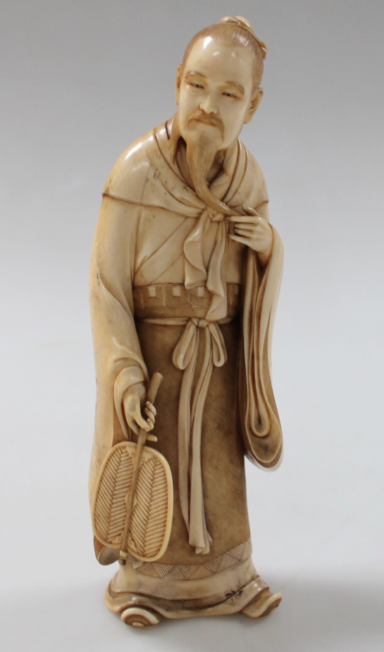 A Japanese finely carved ivory okimino figure, of a bearded warrior holding the trail of his beard