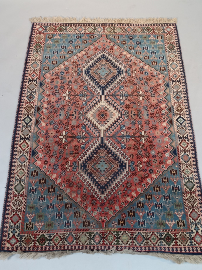 An Iranian hearth rug, of rectangular form, hand woven with a geometric floral design in blue, red