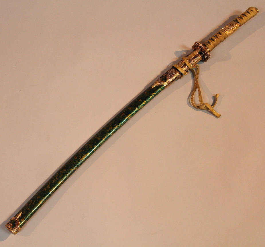 A Japanese samurai sword, with a heavily decorated scabbard, raised with buildings on a green and