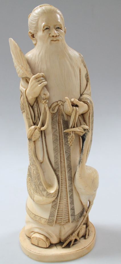 A Japanese carved ivory okimino figure, of a long bearded sage holding a leaf fan, standing aside