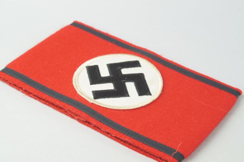 A Third Reich SS Nazi arm band, in red felt with black swastika upon white background.