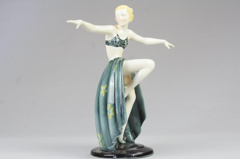 A German Art Deco pottery figure of a dancing girl, with outstretched arms and a long skirt, on a