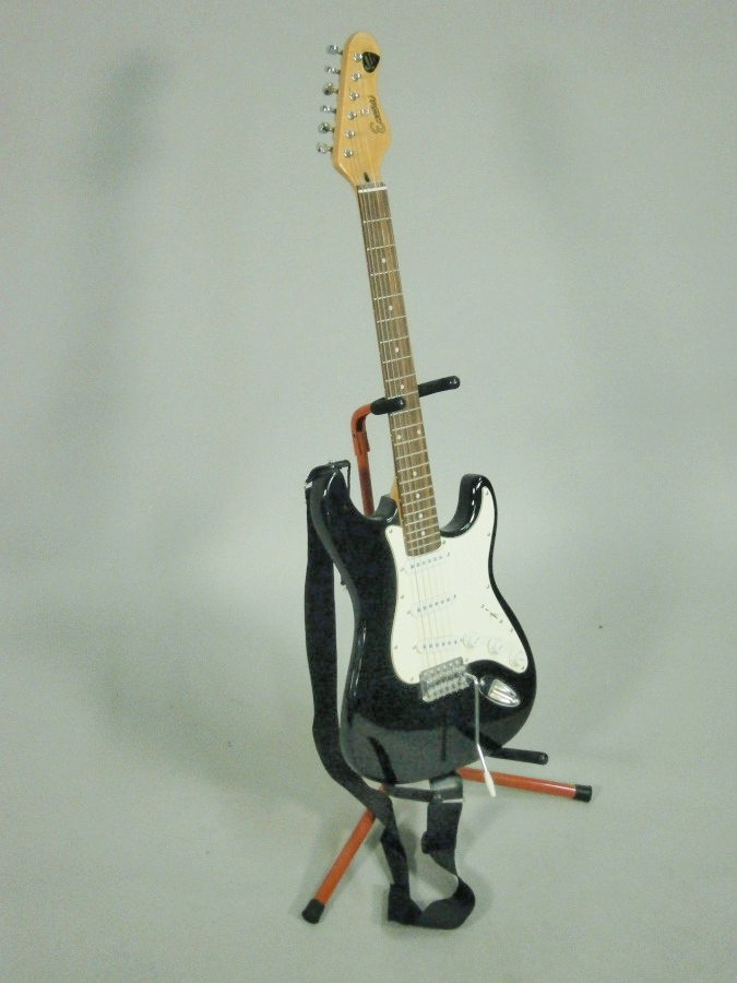 An Encore electric guitar, stand and small amplifier