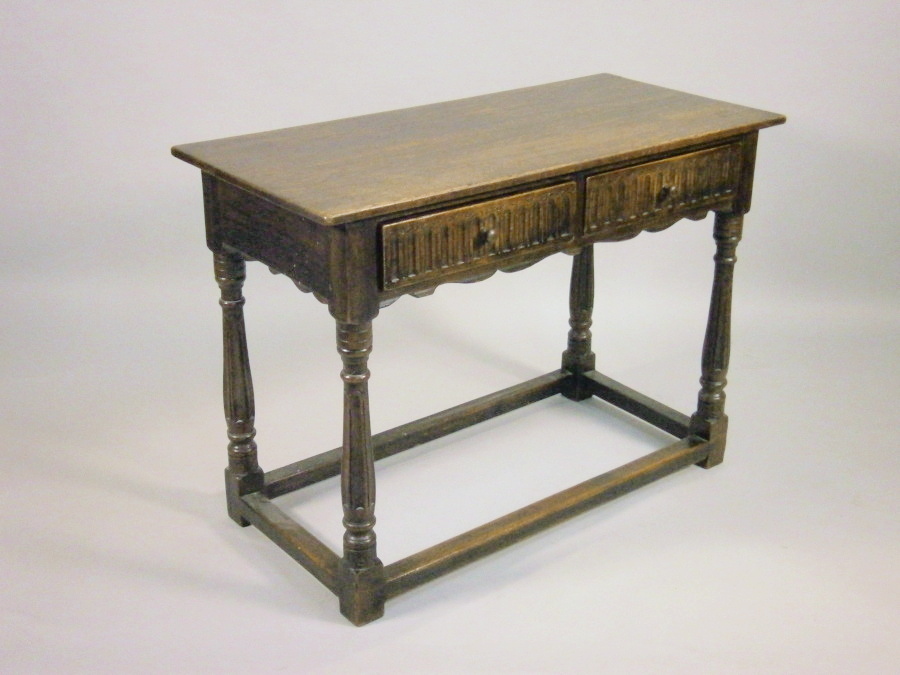 An oak side table, with two carved frieze drawers on turned legs with plain stretchers, 107cm wide