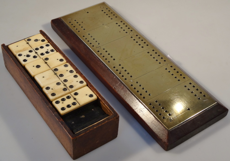 A brass and mahogany cribbage board and bone/ebony dominoes.