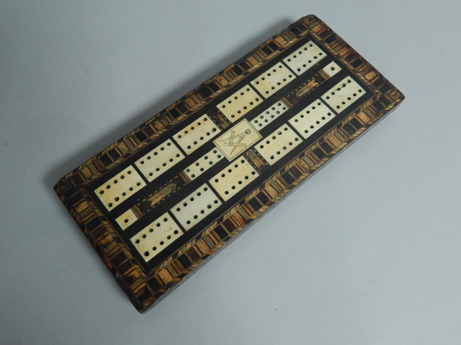 A 19thC ebonised Masonic cribbage board, inlaid with exotic timbers and ivory, on turned feet,