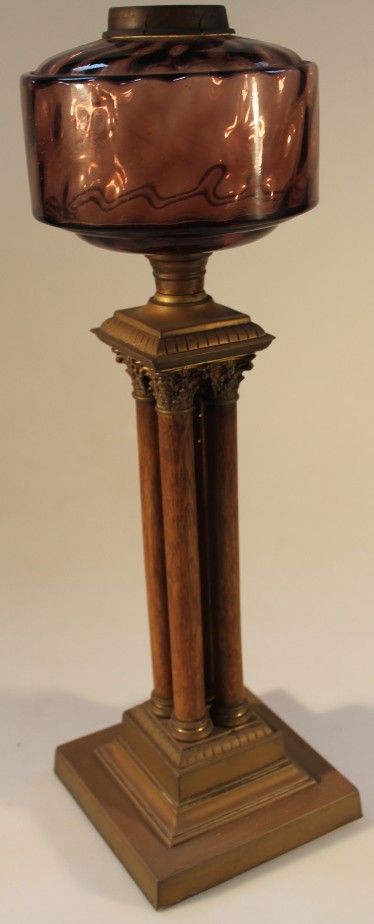 An early 20thC oil lamp base, with coloured glass reservoir, on four wooden columnar base, (AF),