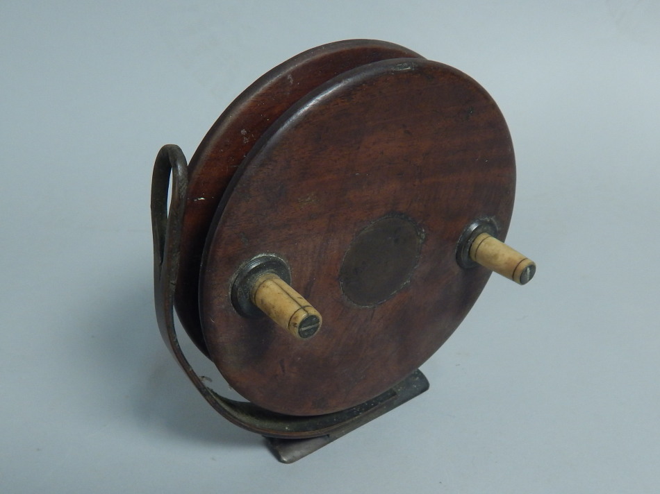 An early 20thC Nottingham type mahogany and brass fishing reel, with turned bone handles, 15cm wide