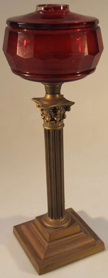 An early 20thC oil lamp base, with cranberry glass reservoir on columnar base, 45cm high.