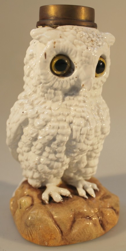 A 19thC German porcelain owl novelty lamp base, with glass eyes, perched on a rocky mound, unmarked,