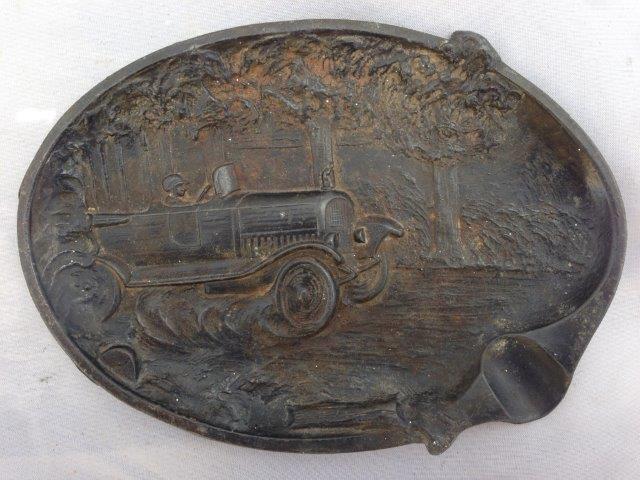 A French cast metal ashtray depicting a vintage motor car driving at speed through some woods,