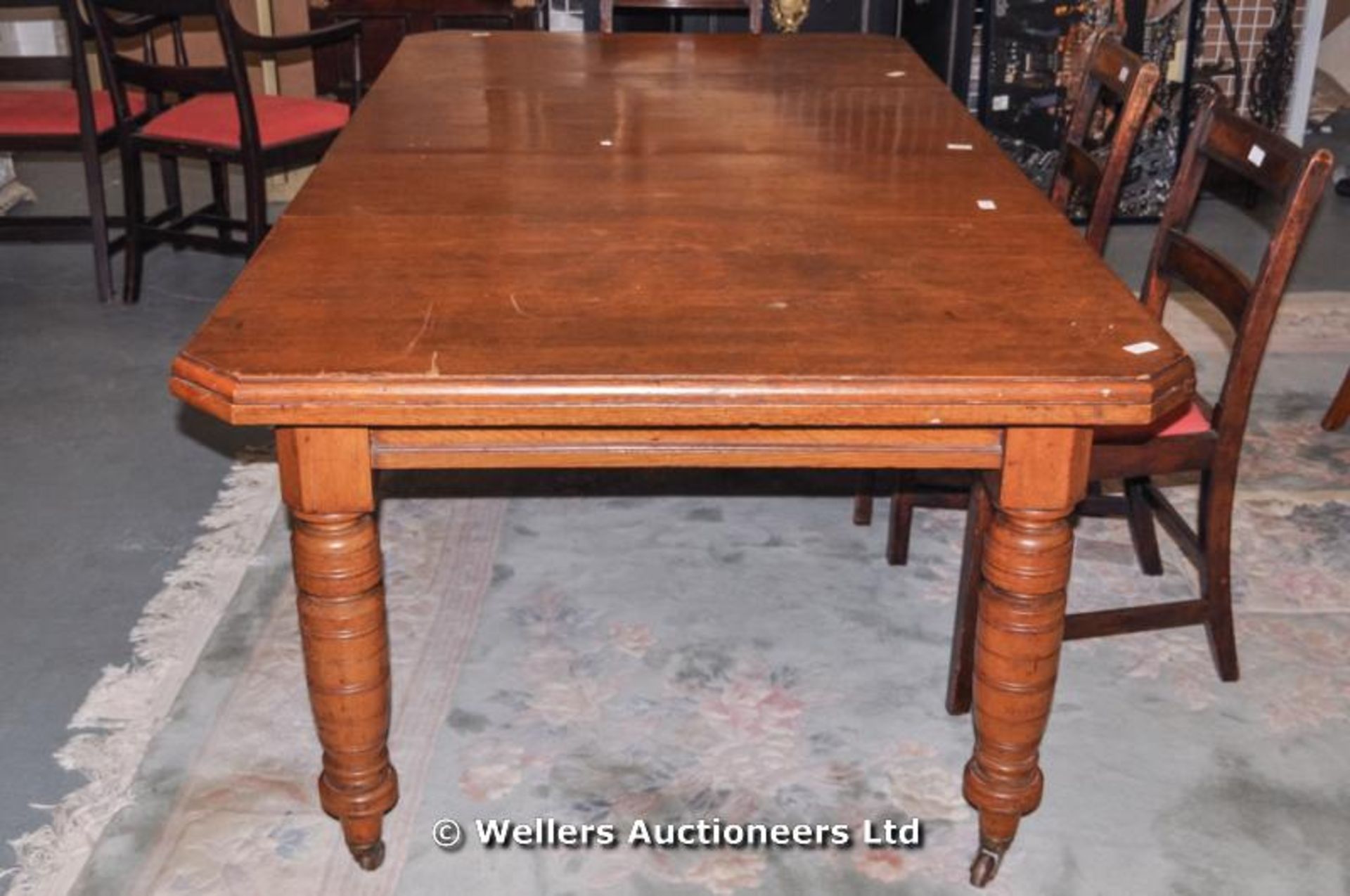 An oak Victorian wind-out dining table with two extra leaves, canted corners