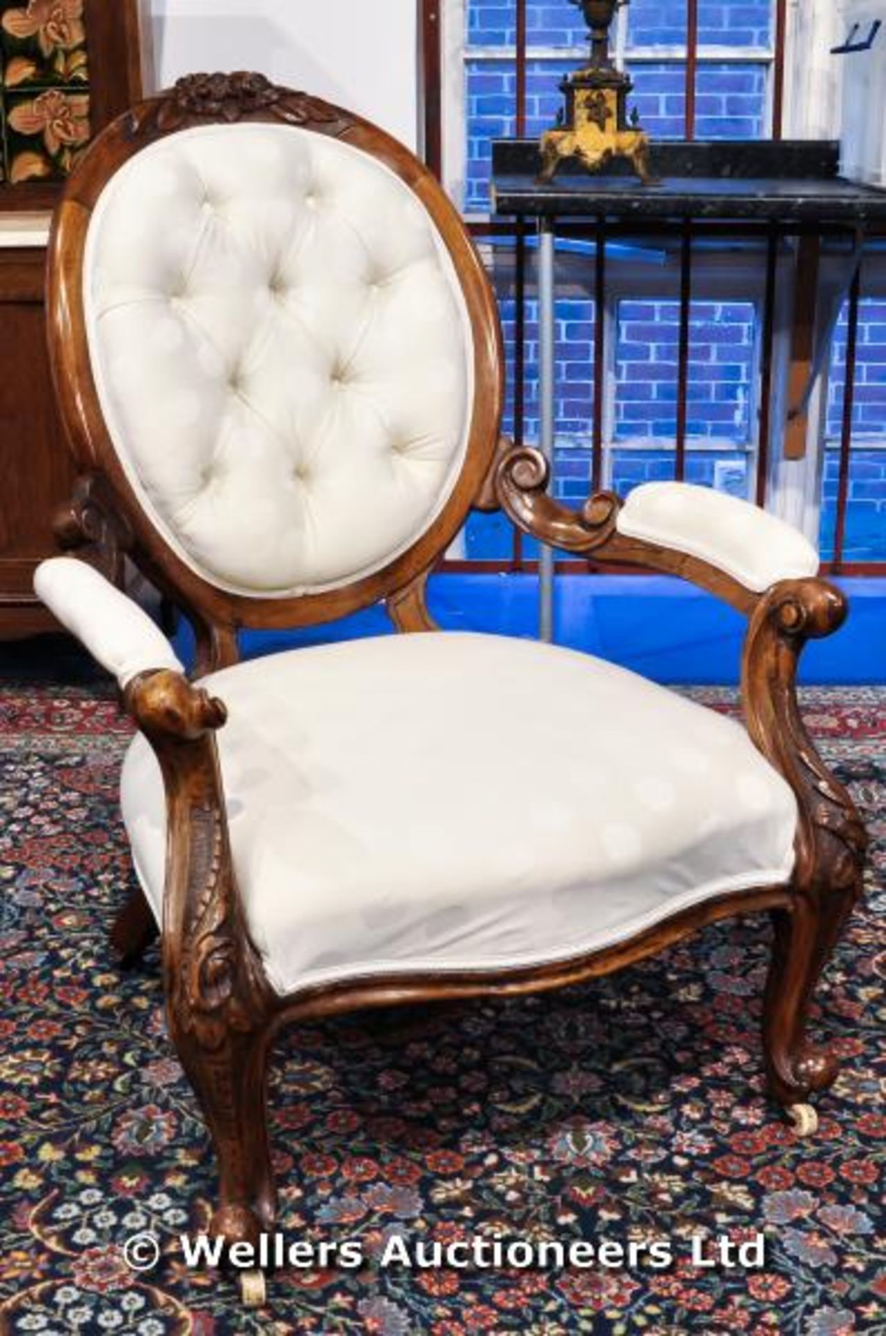 A Victorian button back salon chair with carved legs and frame on original castors