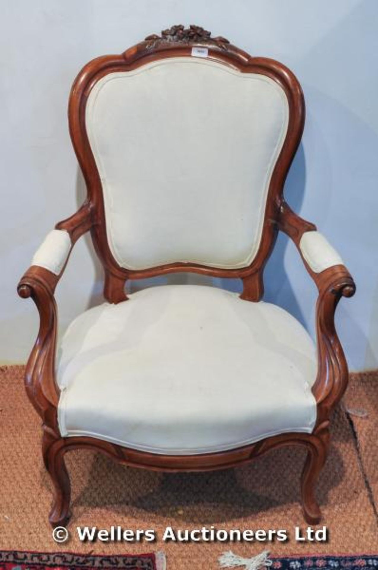 A Victorian walnut open armchair with carved detail of flowers to back, white upholstery