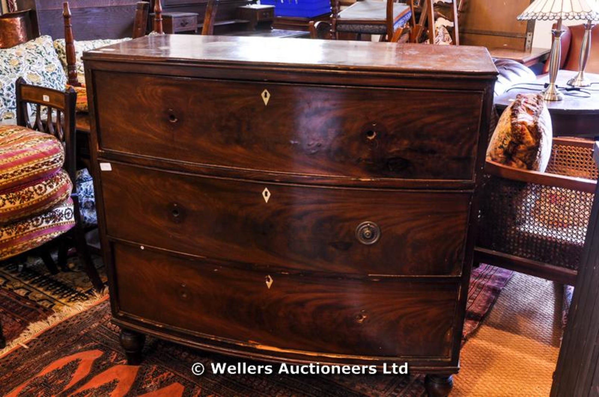 An early 19thC bowfront chest of three drawers, with ivory escutcheons