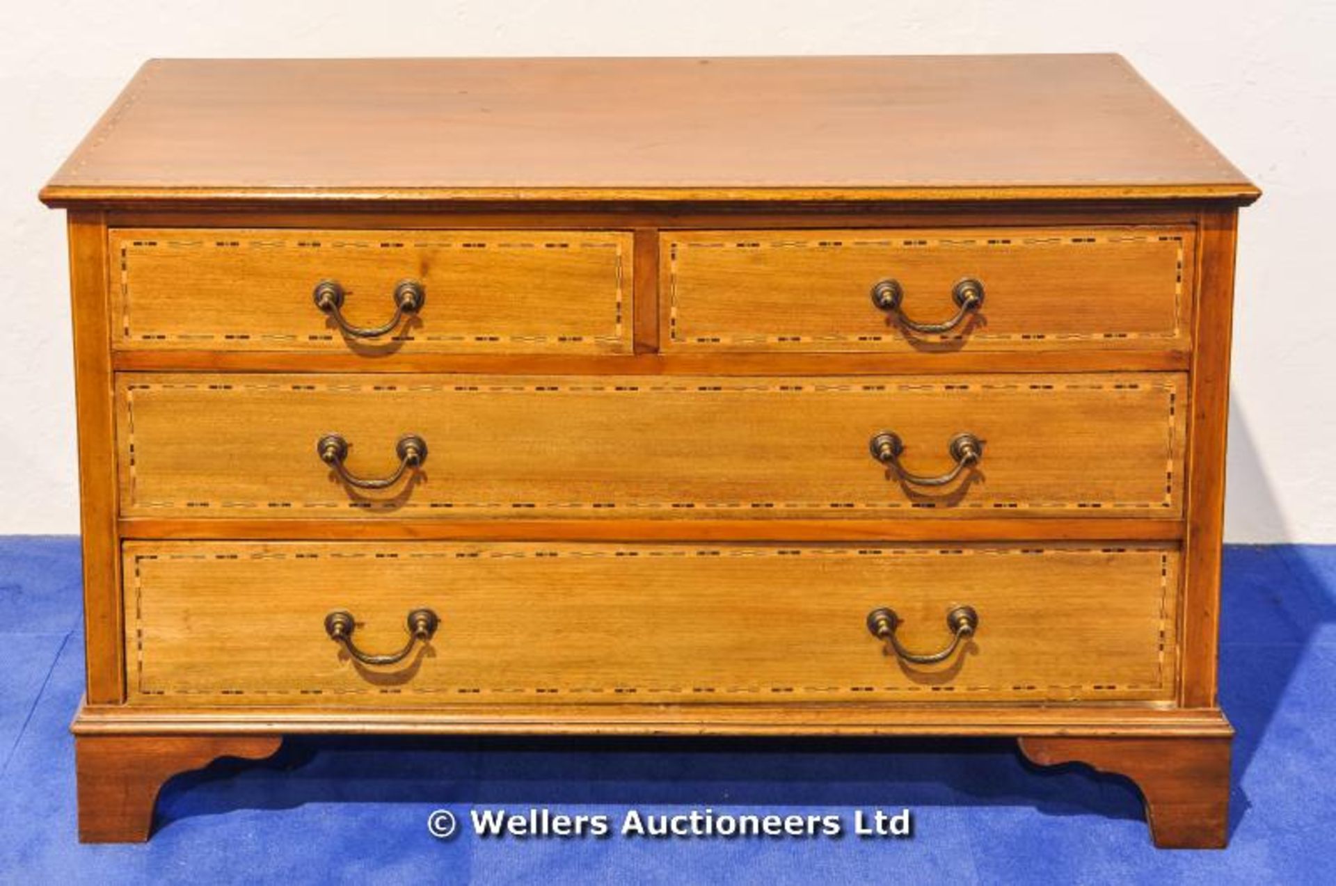 A low chest of drawers, two short over two long, with bronze handles and inlaid detail to drawer